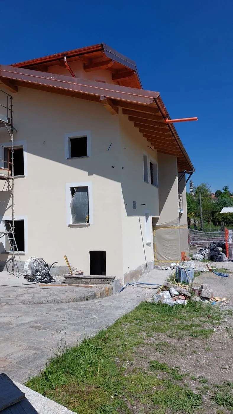 Facciata appena intonacata con tetto in legno e rame