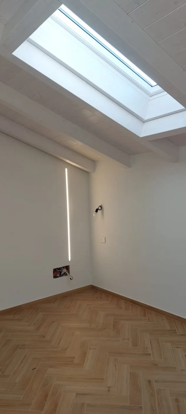 Camera con lucernario e travi bianche